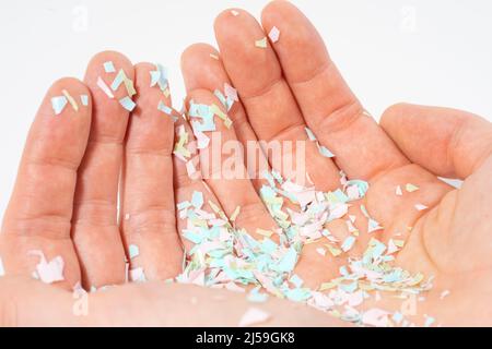 Une photo en gros plan des microplastiques repose sur la main humaine. Concept de pollution de l'eau et réchauffement de la planète. L'idée de dommages environnementaux. Arrière-plan blanc Banque D'Images