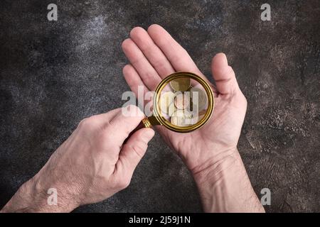 Crise financière, un homme à travers une loupe examine un salaire en centimes d'euro dans son creux, le concept de l'inflation Banque D'Images