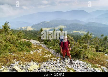 Randonneur avec sac à dos en montée. Randonnée dans les montagnes Carpathian. Randonneur allant jusqu'au sommet de la montagne sur un sentier très raide. Concept de style de vie actif le Banque D'Images