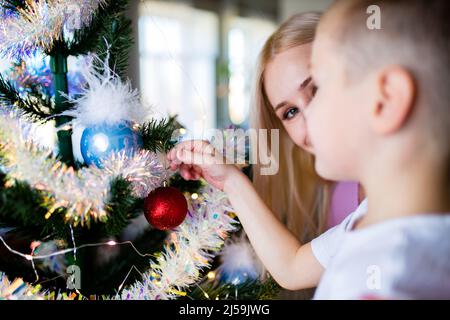 Enfant et mère décorant l'arbre de Noël à la maison auto-isolement en quarantaine en raison du coronavirus Banque D'Images