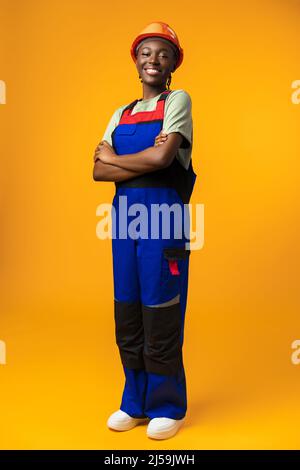 Jeune femme afro-américaine portant un casque d'architecte sur fond jaune Banque D'Images