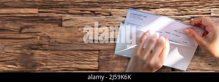 Close-up de l'homme d'affaires d'ouverture de l'enveloppe avec un chèque en bois de plus de 24 Banque D'Images
