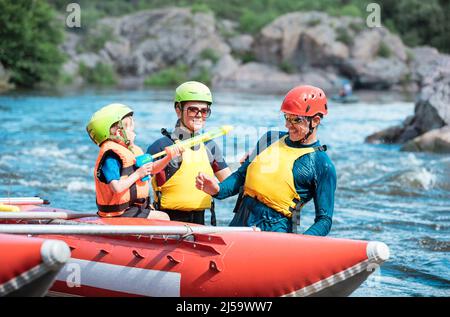 Mère, père et petit fils jouant avec des pistolets à eau au catamaran gonflable Banque D'Images