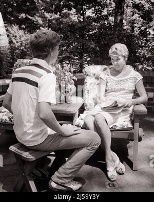 1970S FEMME MÈRE ASSIS SUR LE PATIO EXTÉRIEUR TENANT UN JOURNAL AYANT UNE CONVERSATION SÉRIEUSE AVEC SON FILS ADOLESCENT - J14211 HAR001 HARS MÈRES VIEUX TEMPS FUTUR NOSTALGIE INDUSTRIE VIEILLE MODE CONVERSATION 1 COMMUNICATION JUVÉNILE FORTES FEMMES PATIO SAINTETÉ MAISON LIFE COPY ESPACE FEMMES PERSONNES ATTENTIONNÉES SOINS HOMMES ADOLESCENT GARÇON B&W BONHEUR BIEN-ÊTRE CONSULTATION FIERTÉ AUTORITÉ CONNEXION SOUTIEN CONCEPTUEL ADOLESCENT SINCÈRE ATTACHEMENT PERSONNEL SOLENNEL AFFECTION PORTÉE ÉMOTION CROISSANCE INTENSE JUVÉNILES ADULTE MOYEN-ADULTE FEMME MOYENNE-ADULTE MAMAN TOGETHERNESS NOIR ET BLANC PRUDENT Banque D'Images