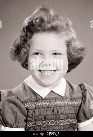 1950S PORTRAIT DE FILLE SOURIANTE REGARDANT HORS DE L'APPAREIL PHOTO PORTANT ROBE AVEC BRODERIE SMACKING ET COLLIER BLANC - J3727 HAR001 HARS COPY SPACE CONFIDENCE EXPRESSIONS B&W BRODERIE BONHEUR TÊTE ET ÉPAULES GAIE ET EXCITANTE FIERTÉ SOURIRES JOYEUX ÉLÉGANT AGRÉABLE AGRÉABLE AGRÉABLE CHARMANT CURL JUVÉNILES LOVABLE AGRÉABLE ADORABLE ADORABLE ATTRAYANT NOIR ET BLANC CAUCASIEN ETHNICITÉ CURLY CHEVEUX HAR001 OLD FASHIONED SMOCKING Banque D'Images