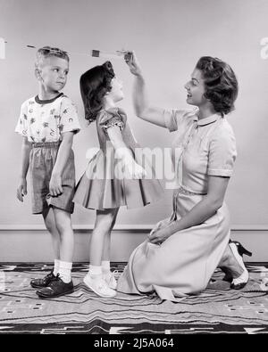 1950S FEMME MÈRE MESURANT LA HAUTEUR DU GARÇON ET DE LA FILLE FILS ET FILLE FRÈRE ET SŒUR DEBOUT DOS À DOS FILLE SUR LES TIPTOES - J7427 HAR001 HARS VIEUX TEMPS NOSTALGIE FRÈRE VIEILLE MODE SOEUR 1 SILLY JUVÉNILE CROISSANCE COMIQUE DE LA COMPÉTITION FILS FAMILLES STYLE DE VIE FEMMES FRÈRES MAISON VIE COPIE ESPACE FEMMES FILLES PLEINE LONGUEUR HOMMES FRÈRES SŒURS MESURE B&W OBJECTIFS DÉCOUVERTE HUMORISTIQUE ET COMIQUE DE LA CONNEXION DE FRÈRE LA PLUS GRANDE COMÉDIE CONCEPTUELLE GROW ÉLÉGANT COOPÉRATION CROISSANCE JUVÉNILES ADULTE MOYEN-ADULTE FEMME DE TAILLE MOYENNE MAMANS PLUS GRANDS TIPTOES NOIR ET RACE BLANCHE HAR001 ANCIENNE Banque D'Images