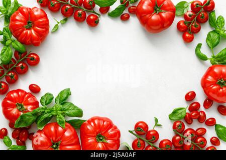 Tomates et basilic sur fond blanc, vue de dessus, plat Banque D'Images