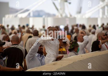 Un pèlerin protégeant la tête de son enfant pendant le rituel lapirant du Hajj en Arabie saoudite Makkah Banque D'Images