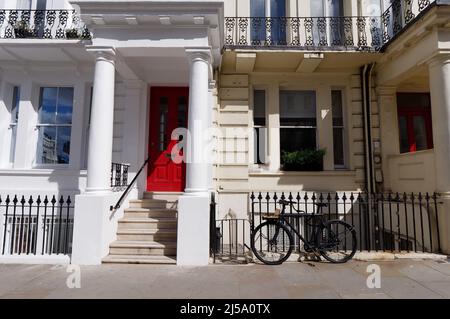 Londres, Grand Londres, Angleterre, avril 09 2022: Cycle noir outisde une élégante maison avec une porte rouge à Notting Hill. Banque D'Images