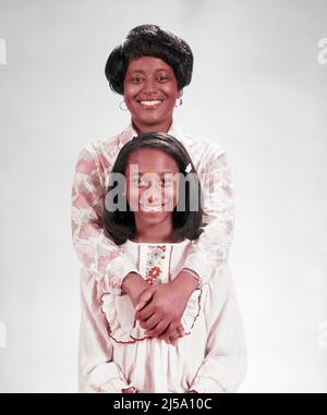 1970S PORTRAIT DE MÈRE AFRO-AMÉRICAINE AVEC SES BRAS AUTOUR DE SA FILLE DEBOUT DIRECTEMENT DEVANT ELLE REGARDANT L'APPAREIL PHOTO - KJ7585 HAR001 HARS BEAUTÉ SUBURBAIN COULEUR URBAINE SES MÈRES VIEUX TEMPS NOSTALGIE EMBRASSANT LA VIEILLE MODE 1 JUVÉNILE COMMUNICATION EMBRASSER FORT HEUREUX FAMILLES JOIE STYLE DE VIE SATISFACTION CÉLÉBRATION FEMMES SANTÉ VIE VIE DEMI-LONGUEUR CÂLIN FEMMES FILLES PERSONNES INSPIRATION S'OCCUPER ADOLESCENTE FILLE CONFIANCE EMBRASSANT CONTACT VISUEL BONHEUR BIEN-ÊTRE GAIE PROTECTION FORCE AFRO-AMÉRICAINS AFRO-AMÉRICAINS PUISSANTE ORIGINE ETHNIQUE NOIRE FIERTÉ AUTORITÉ SOURIT DIRECTEMENT Banque D'Images