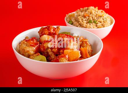 Un bol de poulet et de légumes frits avec une sauce sucrée et couchée et du riz frit Banque D'Images