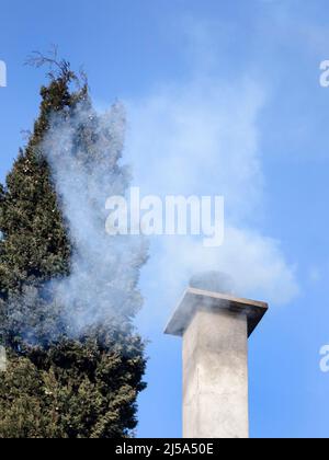 Cheminée Smokey en milieu d'hiver sur ciel bleu Banque D'Images