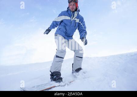 Un snowboarder se déplace sur une piste de montagne avec un snowboard dans un équipement de ski Banque D'Images