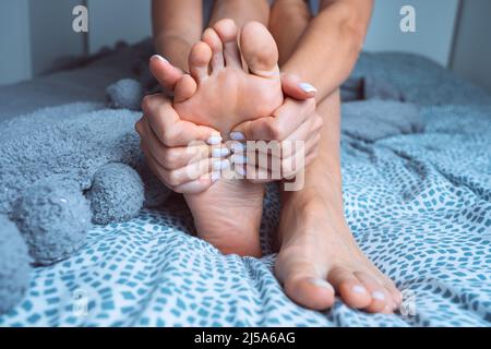 Femme souffrant de douleurs aux pieds ou de douleurs aux pieds et massant un pied douloureux. Crampes aux jambes, douleur dans les jambes ou spasme musculaire Banque D'Images