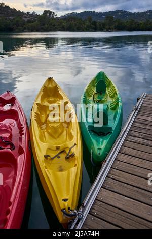 Trois kayaks au coucher du soleil amarrés à un ponton au bord du lac d'Esparron Provence France. Banque D'Images