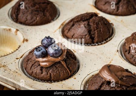 muffins frais avec crème au chocolat et bleuets dans une casserole en céramique Banque D'Images