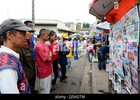 Des hommes et des femmes malgaches lisant les journaux du matin dans un kiosque à journaux avant les élections générales de décembre 2013. Antananarivo, Madagascar. Banque D'Images