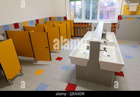 intérieur de la salle de bains de pépinière avec les lavabos en céramique bas et les cabines de toilette jaunes sans enfants Banque D'Images