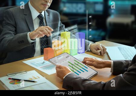 Les hommes d'affaires asiatiques interagissent avec le graphique à barres tridimensionnel de réalité augmentée tout en analysant le retour sur investissement et les performances de l'entreprise Banque D'Images
