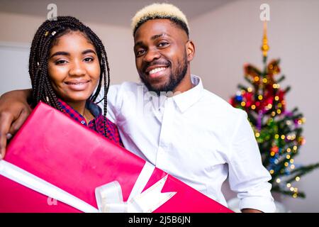 un couple heureux d'afro-américains amoureux présente une boîte cadeau dans le salon Banque D'Images