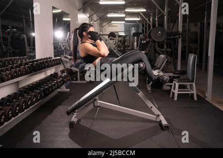 Belle jeune athlète sportswoman s'exerçant dans la salle de gym sur le simulateur, le sport comme un style de vie d'une femme pompant presse, sport concept Banque D'Images