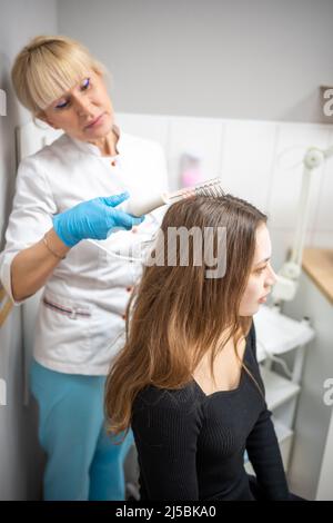 Esthéticienne professionnelle faisant darsonval traitement de cheveux procédure pour la jeune femme dans le salon de beauté Banque D'Images