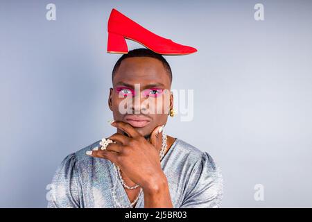 african american cross dressing trans drag queen tenant une chaussure rouge dans le mur blanc de studio Banque D'Images