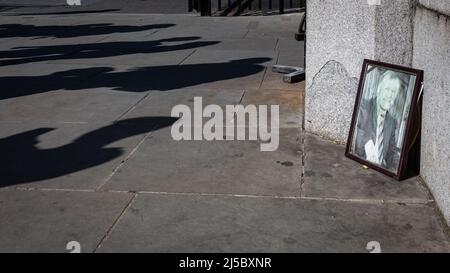 Londres, Royaume-Uni. 21st avril 2022. Une photo du député assassiné Sir David Amess est bâchée sur le trottoir juste à côté des portes d'entrée principales des chambres du Parlement, quelques mois seulement après la tenue d'un service commémoratif à l'abbaye de Westminster. Les gens marchent devant la photographie, qui avait autrefois des fleurs et des hommages à côté de lui apparemment inconscient à elle d'être là. Amess a été mortellement poignardé dans son bureau de circonscription par un attaquant en octobre 2021. Credit: Imagetraceur/Alamy Live News Banque D'Images