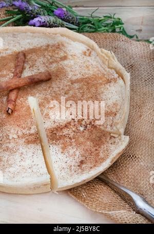 Tarte au lait cuite. Une version au four de tarte au lait traditionnelle sud-africaine ou de melktert, avec de la cannelle et une table rustique Banque D'Images