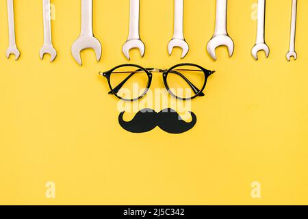 Holiday concept fait avec des lunettes, élégant papier noir stand de photo accessoires moustaches et clés mixtes sur fond jaune mur dans le goujon Banque D'Images