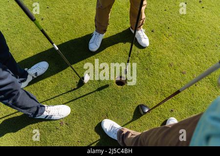 vue en grand angle des amis âgés debout avec des clubs de golf sur la pelouse Banque D'Images