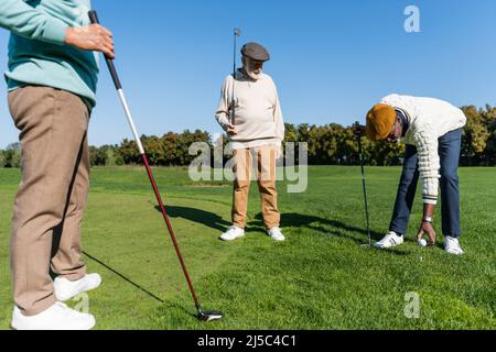 homme afro-américain placé le ballon sur le tee de golf près d'amis multiethniques Banque D'Images