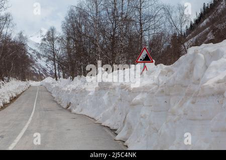 une route asphaltée avec beaucoup de neige après l'hiver et un panneau de signalisation « avalanche » Banque D'Images