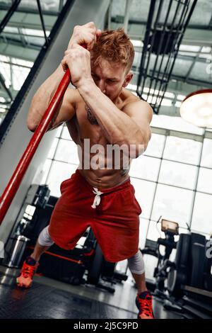Homme entraînement de forme physique avec gros et lourd coups de pneu marteau. Entraînement de concept, résistance croisée Banque D'Images