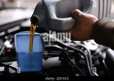 Auto mécanicien verse l'huile de voiture pour la remplacer dans le moteur Banque D'Images