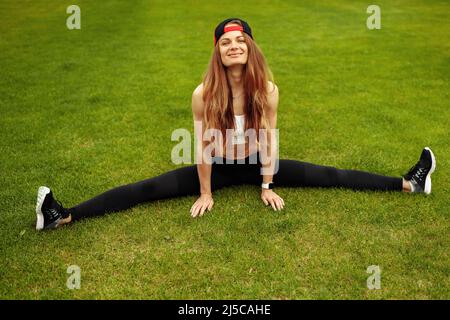 Une femme athlétique surjoyée pratique la flexibilité au stade, smilie, faire des étirements, recommande un mode de vie sain, un concept d'entraînement quotidien Banque D'Images