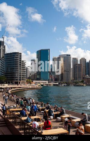 25.09.2019, Sydney, Nouvelle-Galles du Sud, Australie - Vue sur la ligne d'horizon du quartier des affaires autour de Circular Quay et du port. En premier plan, les gens sont assis dans le bar de l'Opéra, le long du front de mer. [traduction automatique] Banque D'Images