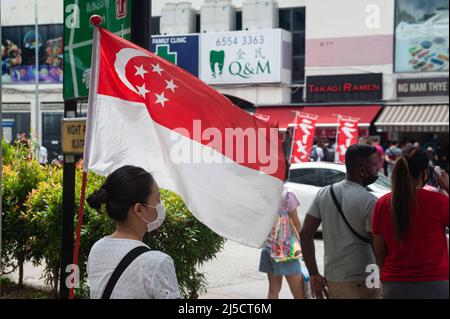 05 août 2020, Singapour, République de Singapour, Asie - Une femme porte un porte-parole pour se protéger et protéger d'autres personnes contre la sous-traitance du coronavirus (Covid-19). À côté de elle porte un drapeau national, qui a été mis en place à l'occasion de la fête nationale du 9 août. [traduction automatique] Banque D'Images