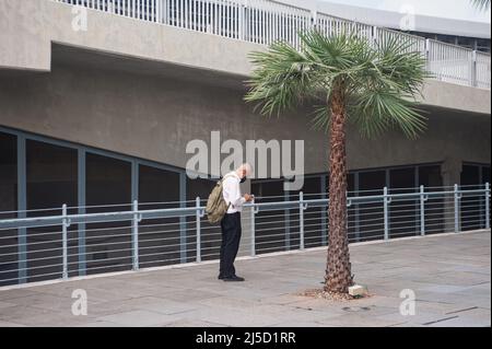 30 mai 2021, Singapour, République de Singapour, Asie - Un homme portant un masque se tient près d'un palmier dans Marina Bay, Surfer sur son téléphone cellulaire pendant la crise corona en cours (Covid-19) peu après qu'une nouvelle vague d'infection ait ramené le pays d'Asie du Sud-est dans un état verrouillé. Cela a entraîné d'autres restrictions, telles que des mesures aux frontières plus strictes et des exigences d'entrée combinées à des tests préalables obligatoires et à un résultat de test négatif sur le départ pour tous les résidents locaux et permanents, ainsi que la fermeture de toutes les écoles primaires, une interdiction des visites de restaurants et Banque D'Images