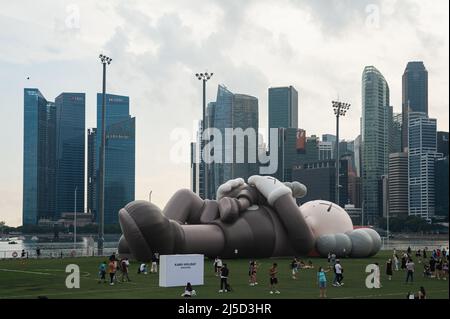16 novembre 2021, Singapour, République de Singapour, Asie - les visiteurs se rendent en cavalet devant le géant de l'art pop-art Companion dans le cadre de la visite de vacances de Kaws, qui est exposée sur le flotteur à Marina Bay, avec les gratte-ciels du quartier des affaires et des finances en arrière-plan. La sculpture gonflable a été créée par l'artiste américain Kaws, dont le vrai nom est Brian Donnelly. [traduction automatique] Banque D'Images