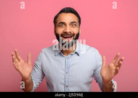 Surprise surjoyeuse indienne gars regardant la caméra isolée sur fond rose. Joyeux et étonné homme multiracial de l'est hors de mon esprit de bonheur, beaucoup, la promotion Banque D'Images