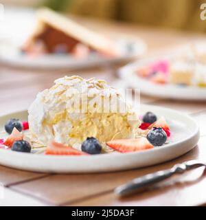 rouleau de meringue avec fraises, bleuets, framboises et canneberges. Dessert décoré de baies fraîches sur une table. Banque D'Images