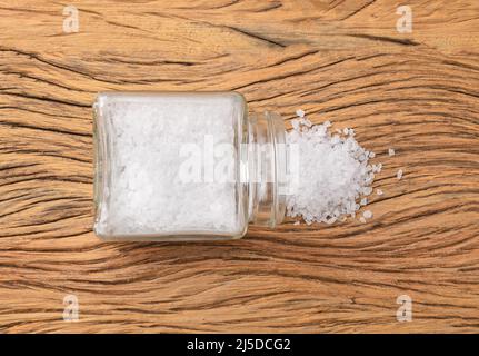 Gros plan de gros sel dans un pot en verre sur une table en bois. Banque D'Images