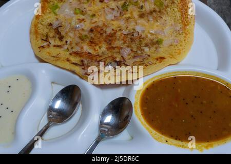 L'Uttapam est servi avec du chutney sur une assiette blanche, un plat de légumes indiens. Banque D'Images