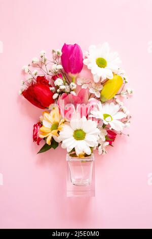 Fleurs printanières avec une bouteille de parfum sur fond rose Banque D'Images