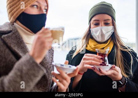 deux femmes boivent du thé turc et du salep tout en portant un masque médical coronavirus time Banque D'Images