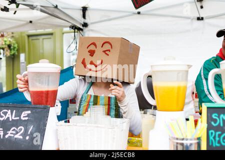 Londres, Royaume-Uni - 20 septembre 2021, Un vendeur dans une boîte en carton avec du ketchup peint sur son visage vend des jus au Broadway Road Sunday Market. Banque D'Images