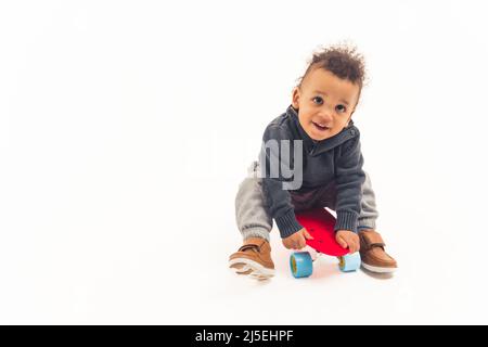 Enfant assis sur un skateboard concept d'enfance et de sport actif. Isolé. Photo de haute qualité Banque D'Images