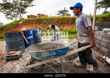 Deux hommes mélangent du ciment, du sable et de l'eau dans un bon mélange de béton pour construire une maison dans la province de Cocle, République du Panama. Banque D'Images