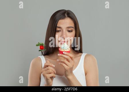 Femme choisissant entre la nourriture saine et le gâteau Banque D'Images